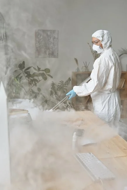 Individual in protective gear standing in a contemporary kitchen setting during the day.